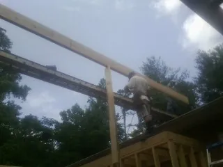 Carpenter setting a ridge beam over a new addition frame — Ice Dam Removal by Roofing Brothers in Glidden