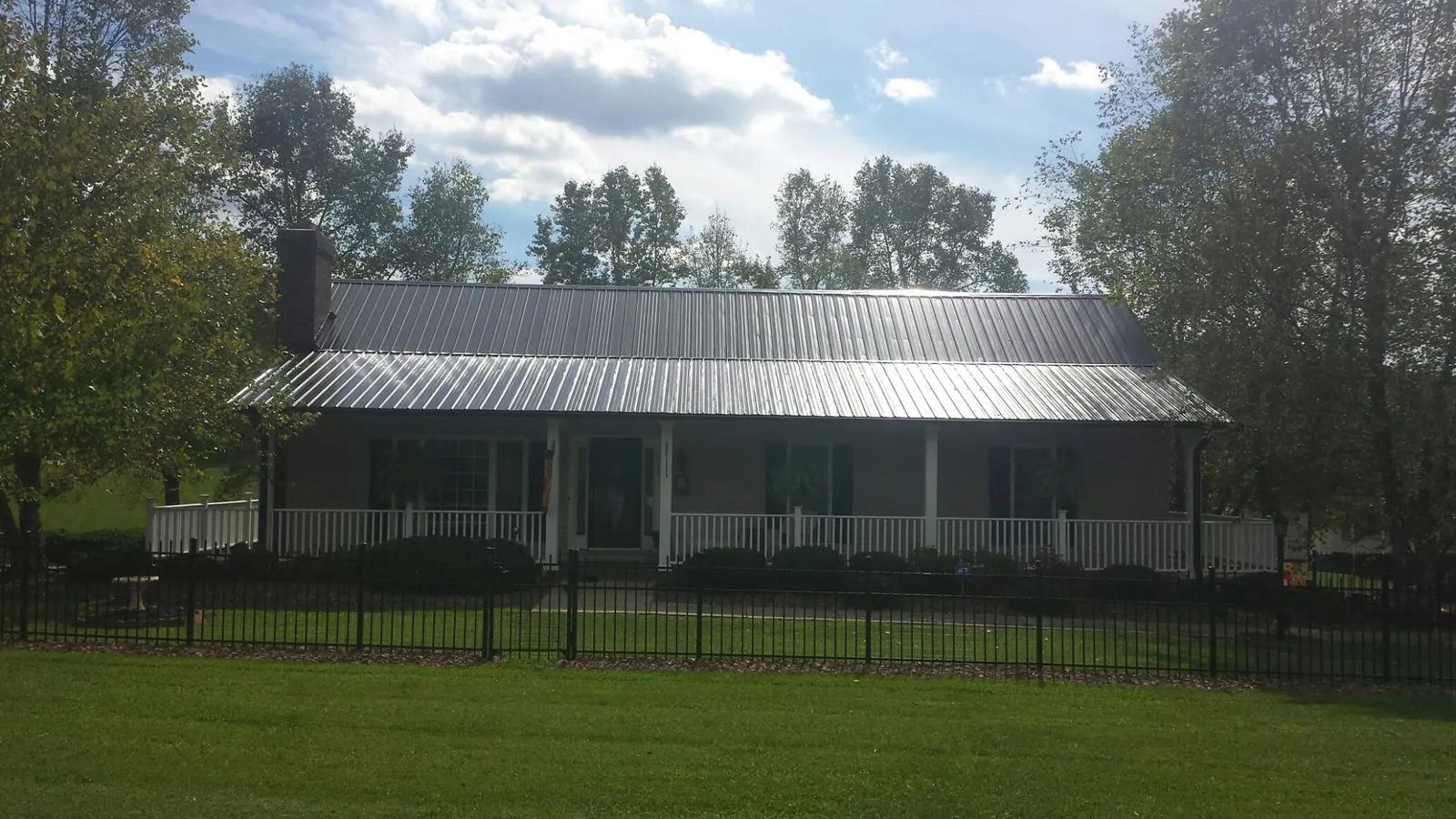 Gray metal roof on a brick ranch with a full width front porch — Gutter Guard Installation work by our crew in Glidden