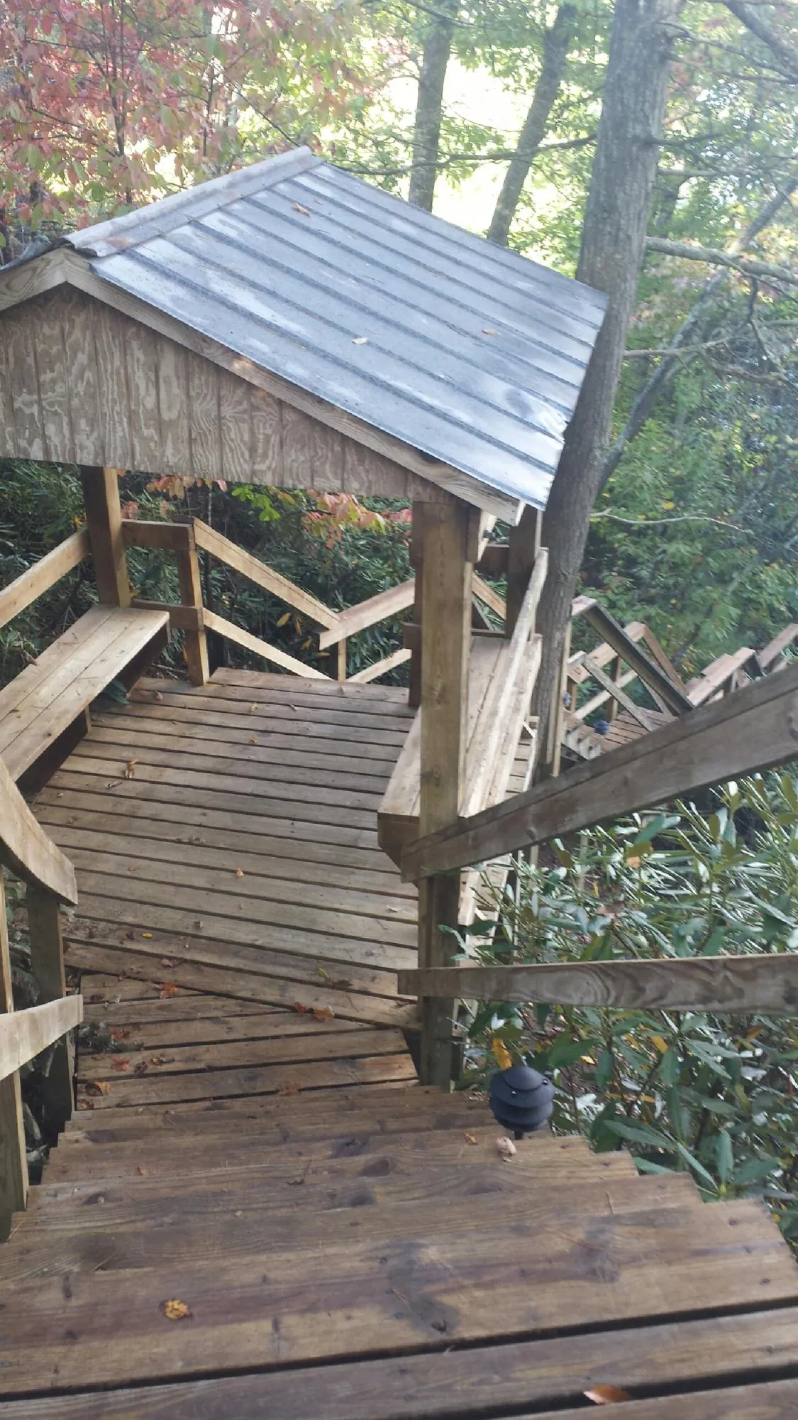 Metal roofed shelter over wooden steps on a wooded walkway — Skylight Repair & Installation work by our crew in Glidden